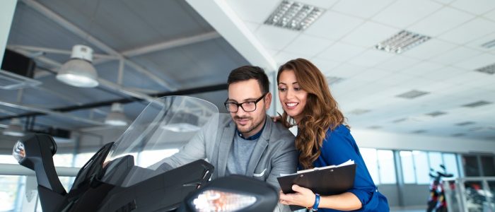 Attractive sales woman helping customer which motorcycle to buy.